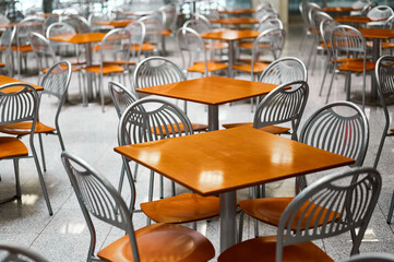 Wooden tables and chairs at large empty foodcourt in mall