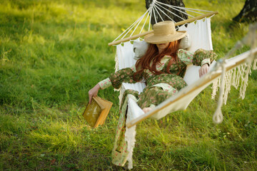 Woman with hat resting in comfortable hammock at green garden.
