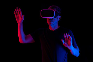 MAN WATCHING VIRTUAL REALITY GLASSES ON DARK BACKGROUND. NEW TECHNOLOGIES CONCEPT.