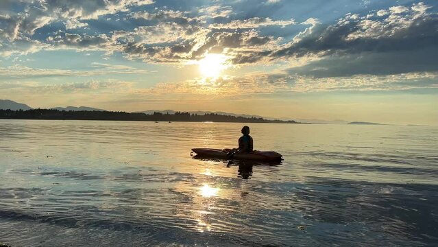 adult woman on a sports holiday she paddles while sitting on a kayak is kayaking for the first time leisure for adults travel agency beautiful weather pacific ocean Parksville beach Surfside RV resort