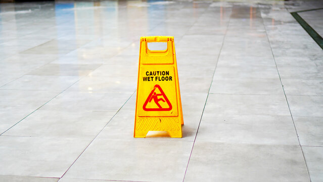 Caution wet floor sign. Wet floor caution sign on walkway near the building after raining.