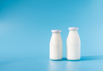 beverage liquid milk white fresh natural two glass bottles on table drink to healthy has protein and calcium for child or toddler, nobody, closeup, blue background and copy space on left for content