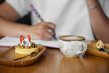 business woman breakfast in cafe mug of coffee with foam and sweet dessert cake, selective focus