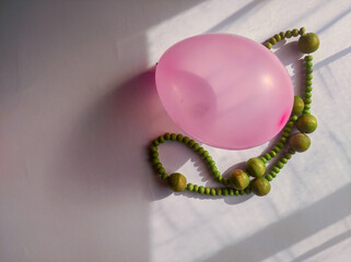 green prayer beads and pink balloon