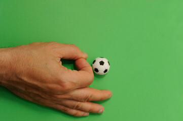 male hand finger football with a miniature toy soccer ball