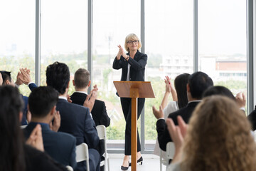 Senior business woman talking at podium speaker. Business people clapping hands to speaker at Business Conference - obrazy, fototapety, plakaty