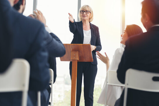 Senior business woman talking at podium speaker. Business people meeting at business conference room