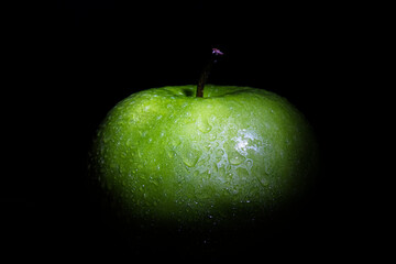 green apple with water drops on isolated black background