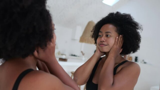 A black woman in front of a mirror looks at her face and thick cheeks, and cannot believe that her body has become so fat. The concept of not accepting yourself for who you are.