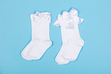 high white children's socks with big bows for festive clothes on a blue background top view