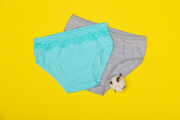 Clothing for children in the form of panties. Clothes for children from soft fabric. Panties for girls. A set of panties for children. View from above. Set of underwear on a yellow background