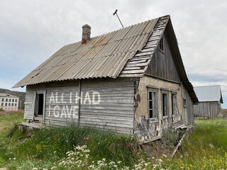 Fototapeta na wymiar Брошенный старый серый дом на севере России с надписью на английском языке