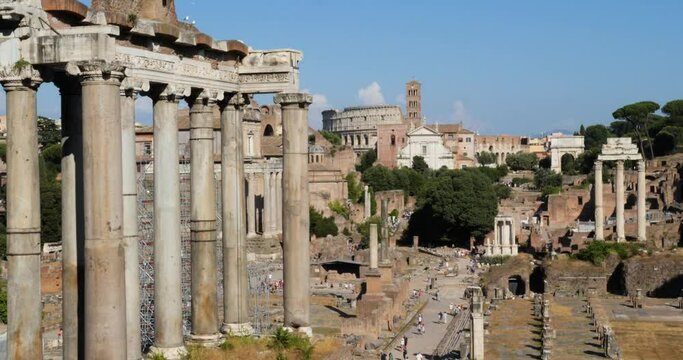 Temple of Saturn, Temple of Castor and Pollux, Arch of Titus and Via Sacra in the Roman Forum archaeological site and Colosseum in the background. Rome, Italy.