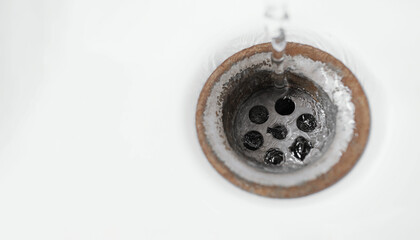 Water drains down. Old rusty drain hole in the washbasin. Household plumbing.