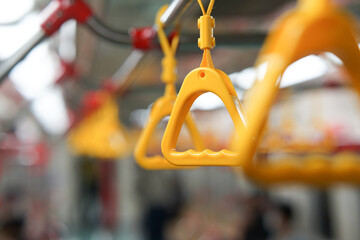 Fototapeta na wymiar selective focus on yellow hanging handle grip on public transportation such as bus and train can be source of virus transmission and health issues.