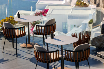 Tables on the restaurant terrace with a picturesque view of the sunset in Imerovigli. Santorini, Greece.