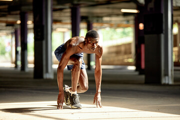 Handsome afro American sportman standing on the street while taking break after training. Black male having rest after workout