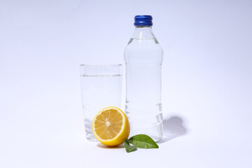 Glass bottle and glass of water, and lemon with leaves