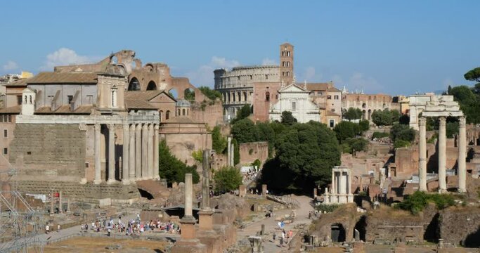 Tourists visiting Roman Forum archaeological site, Colosseum in the background. Rome, Italy.Temple of Castor and Pollux, Arch of Titus, Antoninus and Faustina Temple, Via Sacra.