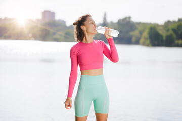 sports girl drinks water after training in the city park