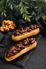 Two eclairs with dark chocolate on black board