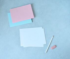 Paper sheets with drawn circle, notebooks, white pencil, and pink eraser