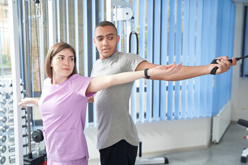 Man doing rehabilitation exercise with instructor in clinic
