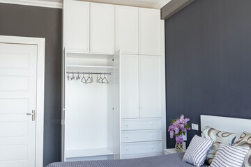 Close-up, empty white wardrobe with open doors in a gray room, copy paste