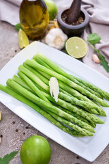Green organic natural Asparagus in ceramic white plate on kitchen table