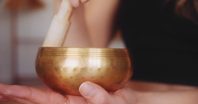 Close up gimbal shot of feminine hands playing Tibetan singing bowl