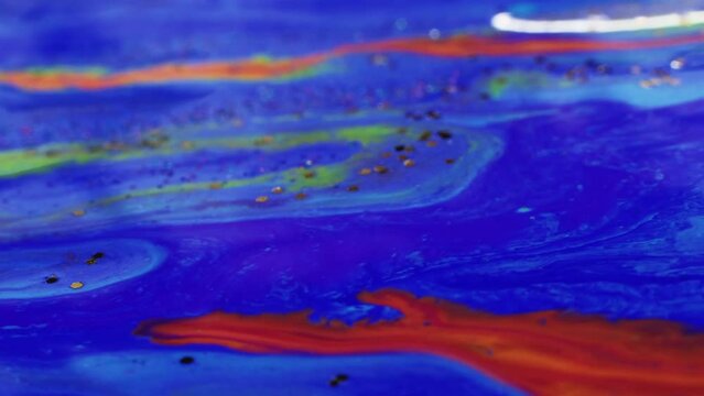 Fluid painting. Magic colors. Creative design. Bright red liquid stream of paint floating and mixing together with glittered blue violet in macro shooting.