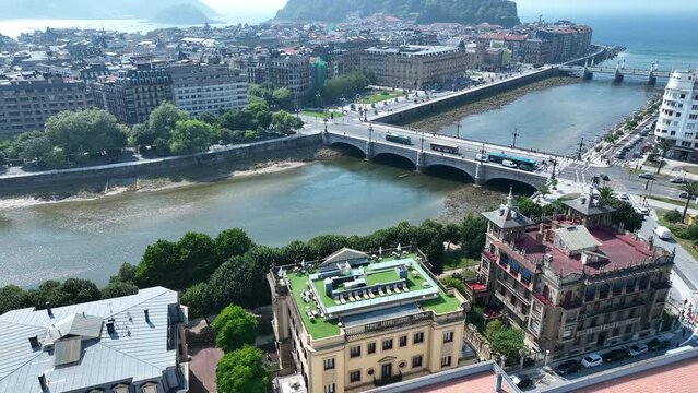 Aerial drone shot of the Urumea River and the Santa Catalina Zubia Bridge arcing around to reveal the Bay of Biscay and the coastal city of San Sebastian, Basque Country