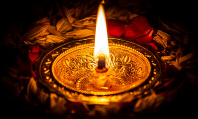 Lit diya lamp against dark background. Lamp made out of silver metal lit during festival.
