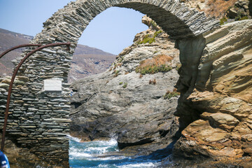 Fototapeta na wymiar andros island stone arch in the sea of andros chora in greece