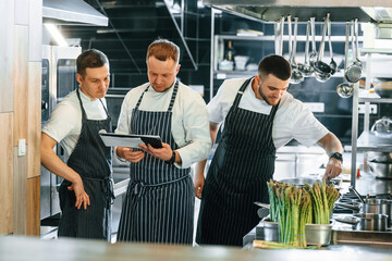 Looking at the documents. Kitchen workers is together preparing the food