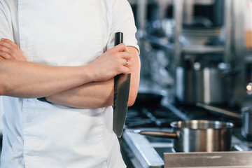 Close up view. Holding a knife. Chef is on the kitchen preparing food