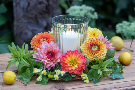 Arrangement mit Blumenkranz mit Dahlien, Efeu und Echtem Leinkraut und Kerze im Glas