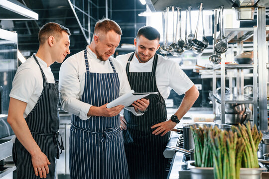 Reading the documents. Kitchen workers is together preparing the food