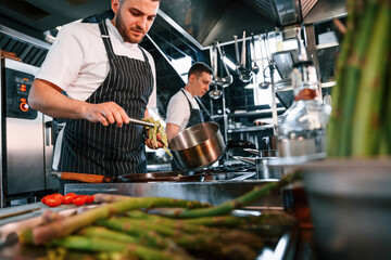 Working with asparagus. Employees is together on the kitchen preparing food