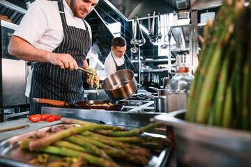 Working with asparagus. Employees is together on the kitchen preparing food