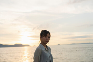 夕暮れの海を散策する女性