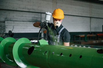 In protective mask. Painting details. Man in uniform is in workstation developing details of...