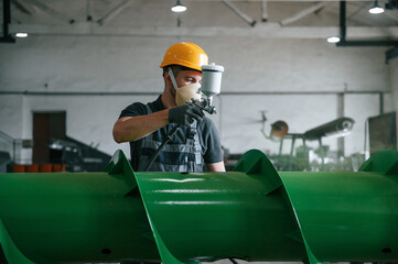 Painting details. Man in uniform is in workstation developing details of agriculture technique