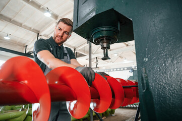 Attention to detail. Man in uniform is in workstation developing parts of agriculture technique