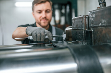 Clean parts. Man in uniform is in workstation developing details of agriculture technique