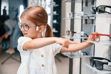Cute customer. Little girl in the glasses store choosing eyewear