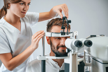 Man's vision checked by female doctor in the clinic by using special optometrist device