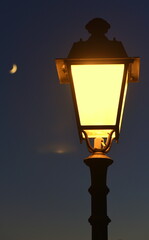 Fototapeta na wymiar Leuchtende Straßenlaterne vor Nachthimmel mit Mond