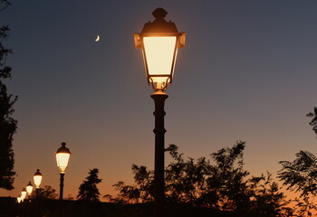 Reihe mit schmiedeeisernen Laternen vor Abendhimmel mit Mond