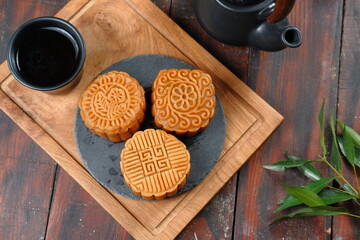 Mooncake, Moon cake (yue bing }-Chinese traditional pastry with tea cups on dark background, Mid-Autumn Festival concept, close up.